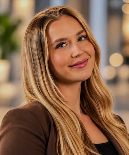 Woman with long blonde hair wearing a brown blazer in a close-up portrait